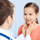 Pediatra palpando el cuello a una niña