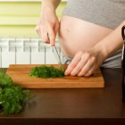 Mujer embarazada picando verduras