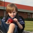 Niño tomando una manzana en el patio del colegio