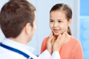 Pediatra palpando el cuello a una niña