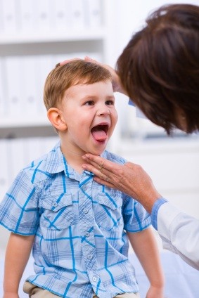 Pediatra explorando la garganta de un niño