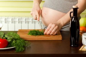 Mujer embarazada picando verduras