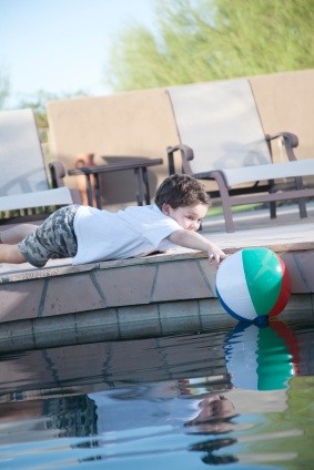 Niño jugando junto a una piscina