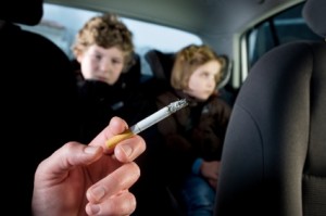 Niño recibiendo humo de tabaco dentro del coche