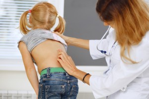 Pediatra explorando la espalda de una niña