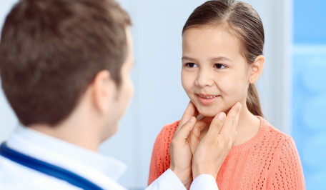 Pediatra palpando el cuello a una niña